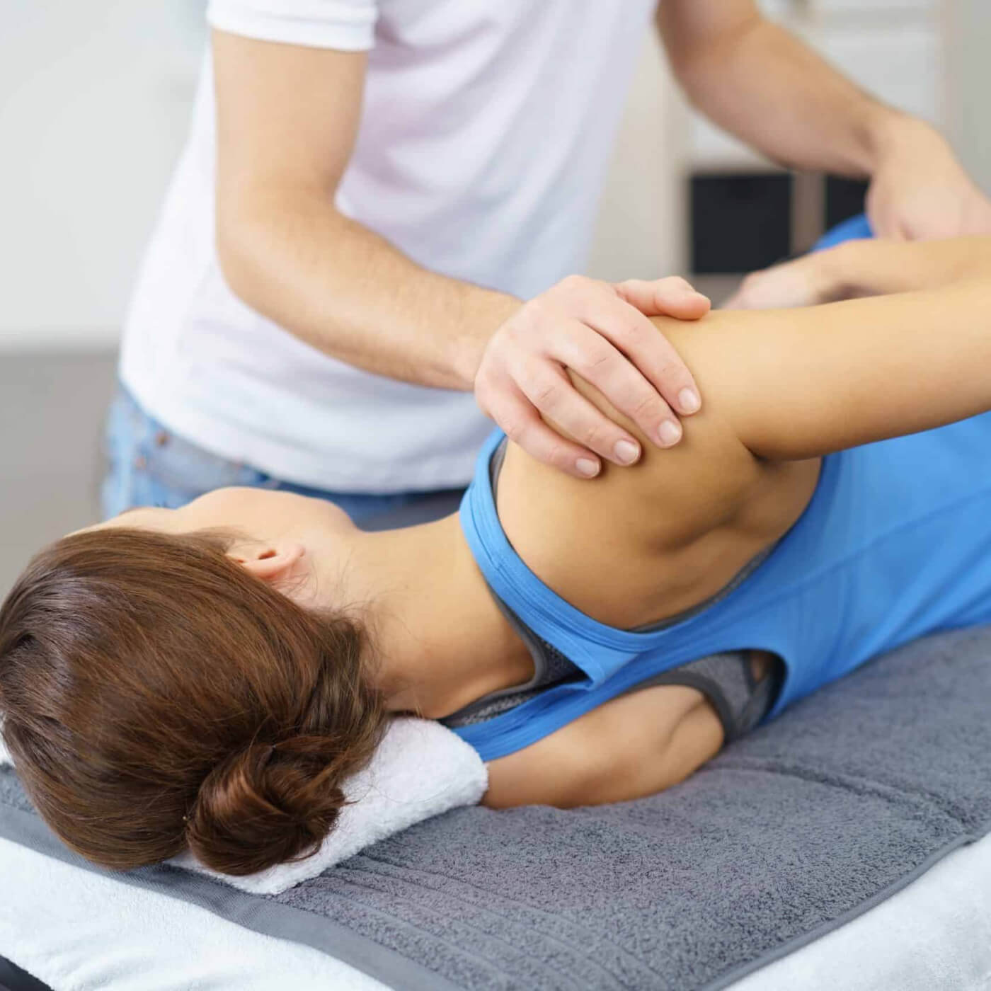 Eine Patientin, die auf einer Liege liegt und bei der manuelle Therapie angewendet wird.